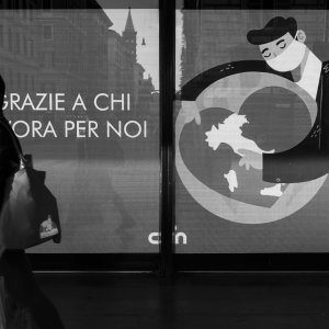 ROME - May 2, 2020: A woman walks the side street of the train station termini in front of an inscription “Thank you for those who work for us” referring to doctors and nurses.