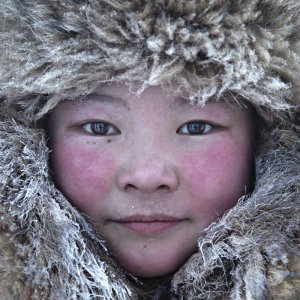 This is a young girl belonging to the Nenet ethnic group. Nenets, to shelter from the cold, dress in reindeer skins, warm and heavy. Women can wear arctic fox fur hats.